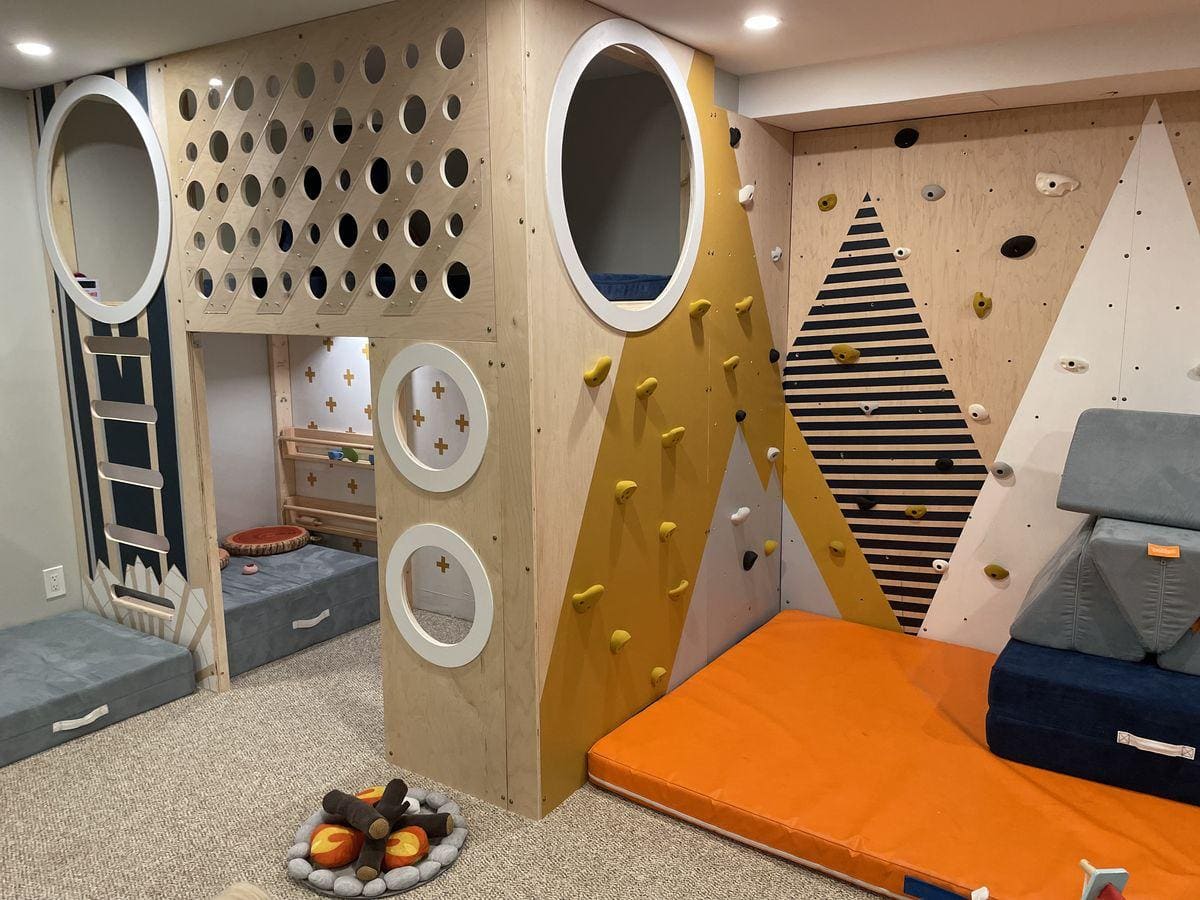 Custom-built children's playroom with a plywood loft playhouse and a climbing wall