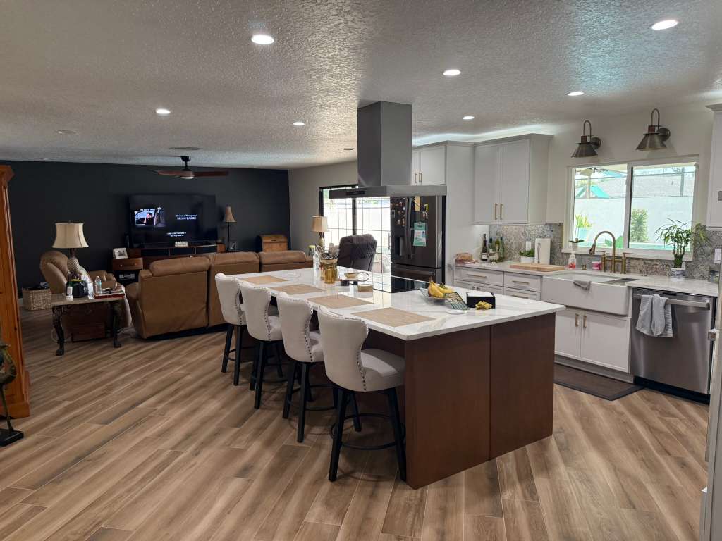 Open-concept kitchen and living room remodel with a waterfall quartz island, bar seating and farmhouse sink